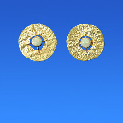 Pair of gold earrings with central opals on a blue background