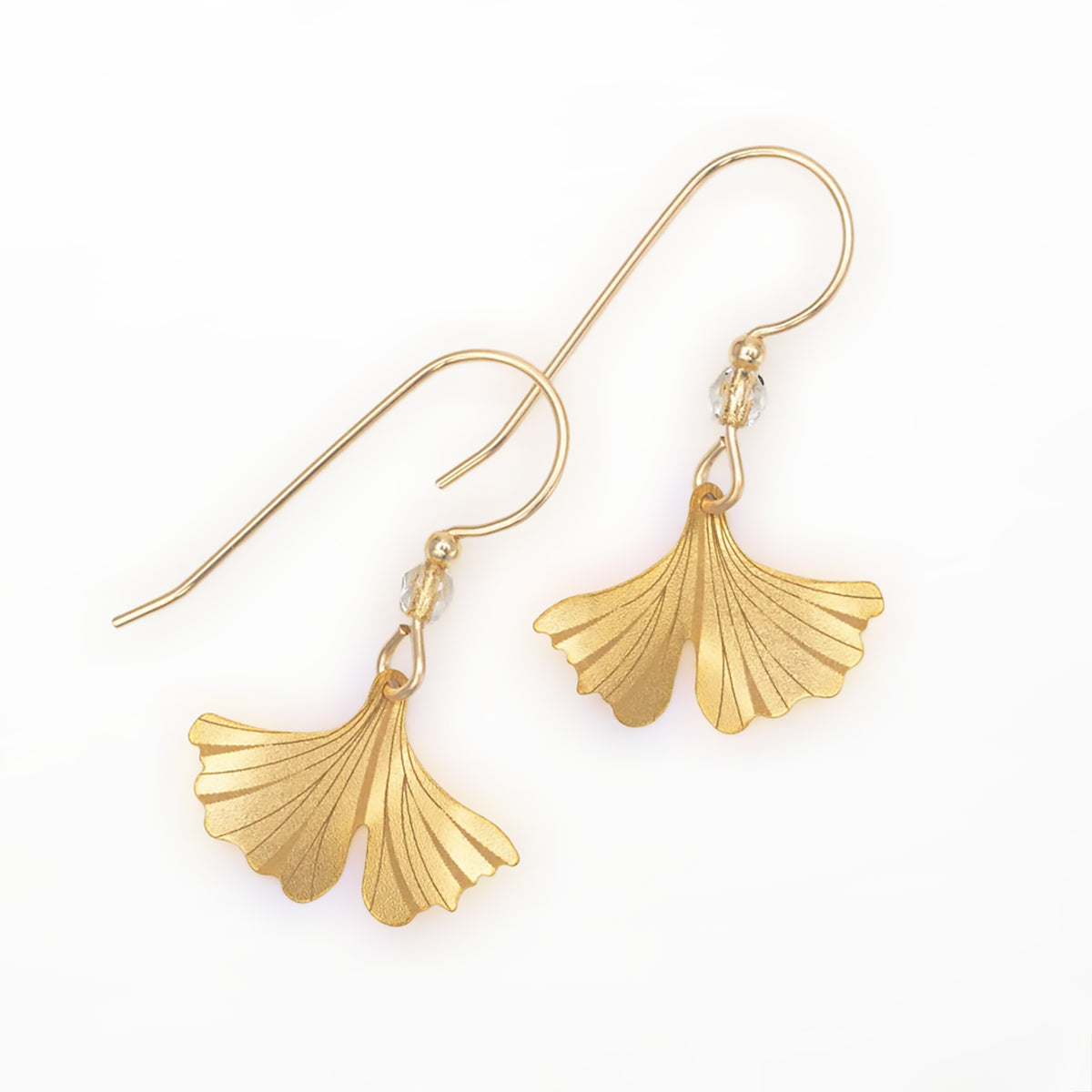 A pair of gold-tone dangle earrings with gingko leaf-shaped leaf pendants, shown on a clean white background.